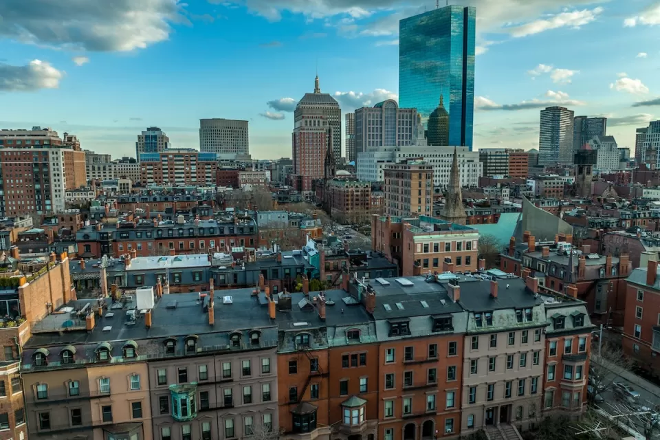 Aerial view of downtown Boston, Massachusetts with older buildings in foreground and modern glass towers in background.